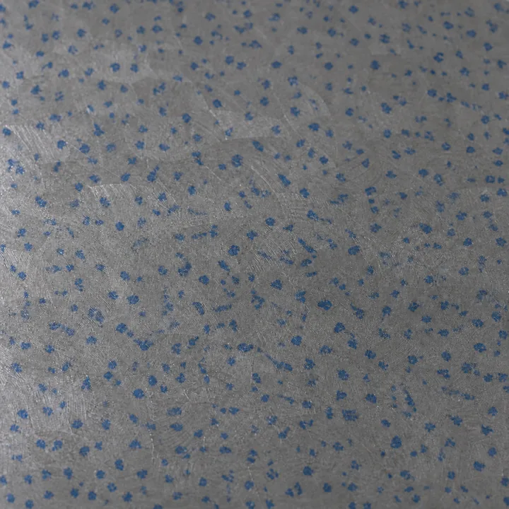 Close-up of a hand-scraped cast-iron surface later in the work: hundreds of small blue specks scattered closely and evenly over the grey scraped iron, which is still most of the face.