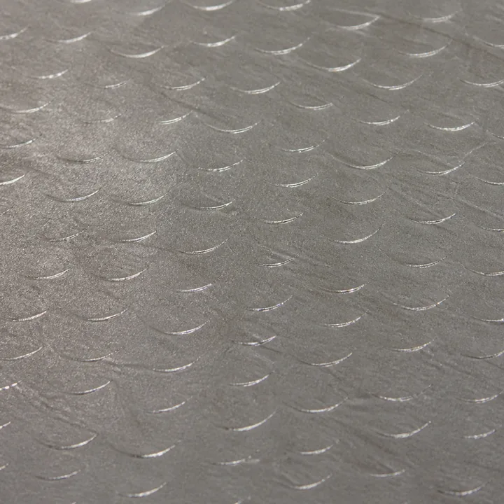 Close-up of a finished hand-flaked cast-iron slideway: crescent scraper marks in overlapping diagonal rows, each a thin bright sliver of cut metal.